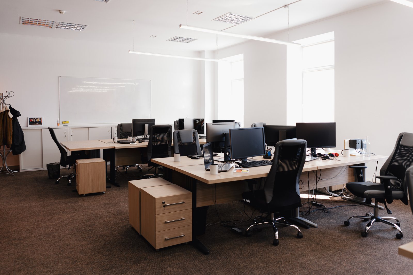 Escritório moderno com mesas, computadores e cadeiras ergonômicas